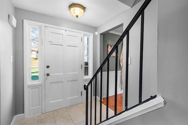 entrance foyer featuring a healthy amount of sunlight, light tile patterned floors, baseboards, and stairway