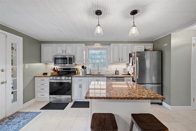 kitchen featuring light tile patterned flooring, stainless steel appliances, a sink, dark stone counters, and pendant lighting