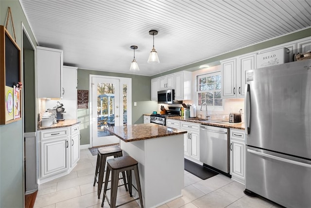 kitchen with stainless steel appliances, plenty of natural light, a sink, and a center island