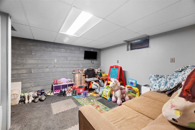 rec room featuring wood walls, carpet, and a drop ceiling