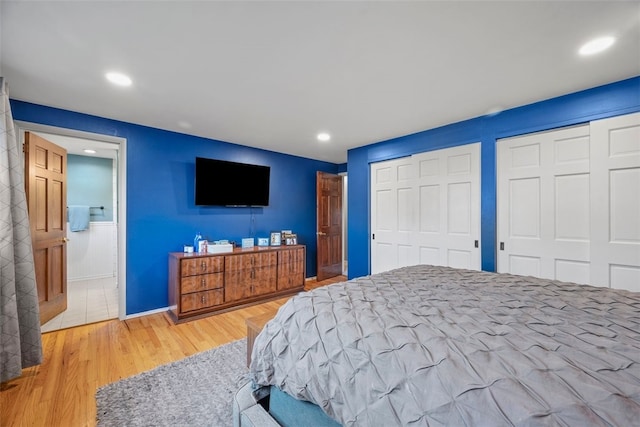 bedroom with recessed lighting, wood finished floors, ensuite bath, and two closets