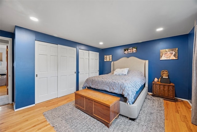 bedroom with recessed lighting, two closets, baseboards, and wood finished floors