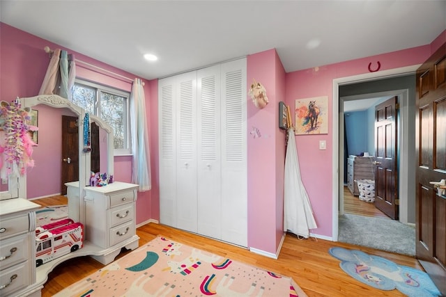 bedroom featuring a closet, recessed lighting, light wood-style flooring, and baseboards