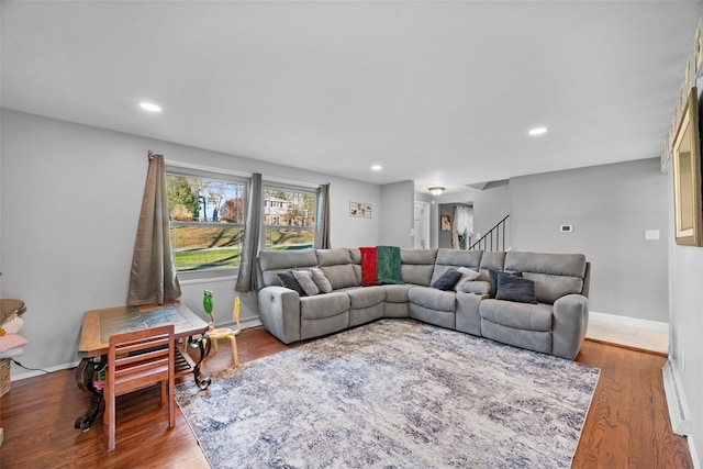 living room featuring stairs, baseboards, wood finished floors, and recessed lighting