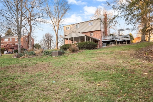 back of property featuring a yard, a chimney, a deck, and brick siding