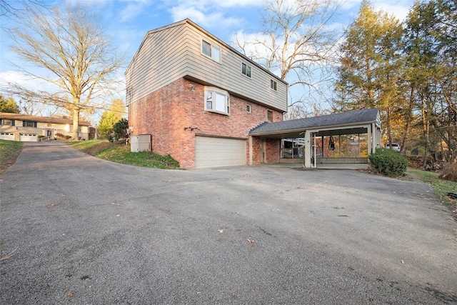 view of side of home featuring a garage, mansard roof, aphalt driveway, a carport, and brick siding