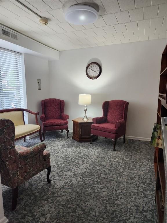 living area featuring carpet flooring, visible vents, and baseboards