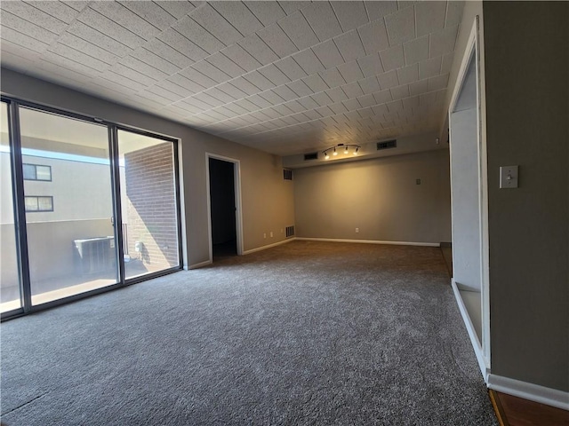 spare room with carpet, visible vents, and baseboards