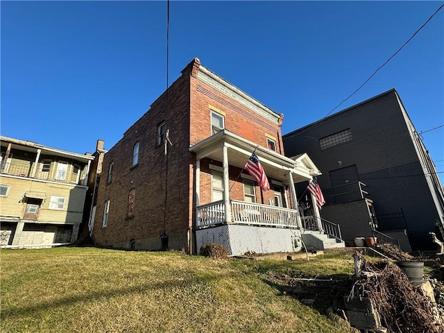 view of home's exterior with a porch, brick siding, and a lawn