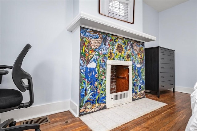 interior space featuring a high ceiling, visible vents, baseboards, and wood finished floors