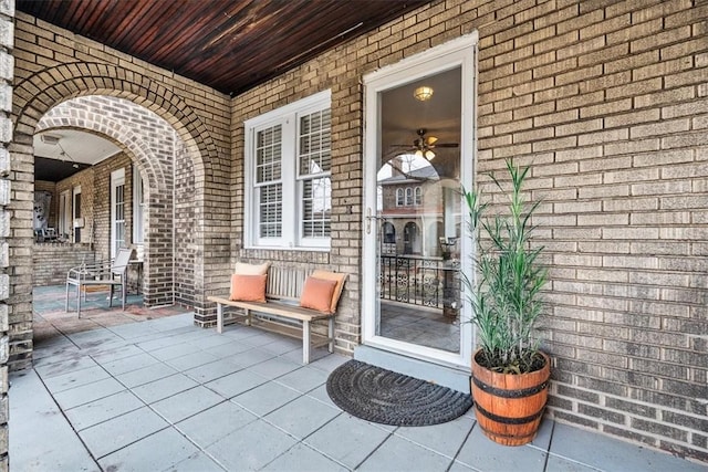 doorway to property featuring covered porch and brick siding