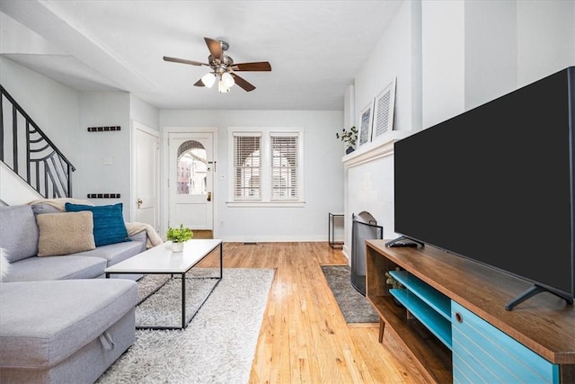 living area featuring ceiling fan, stairway, wood finished floors, and baseboards