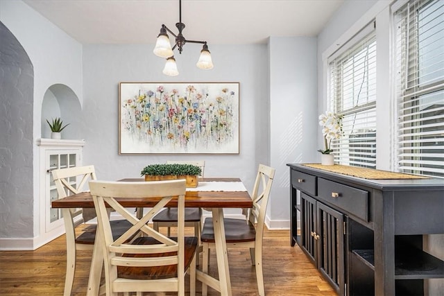 dining space featuring a chandelier, light wood finished floors, and baseboards