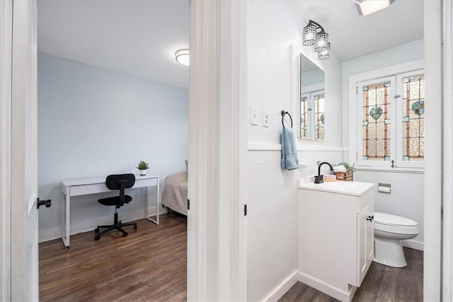 bathroom with connected bathroom, toilet, wood finished floors, vanity, and baseboards