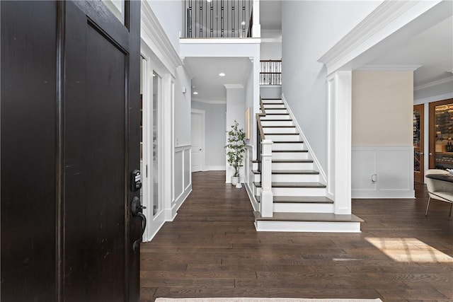 entryway featuring a decorative wall, a wainscoted wall, stairs, hardwood / wood-style floors, and crown molding