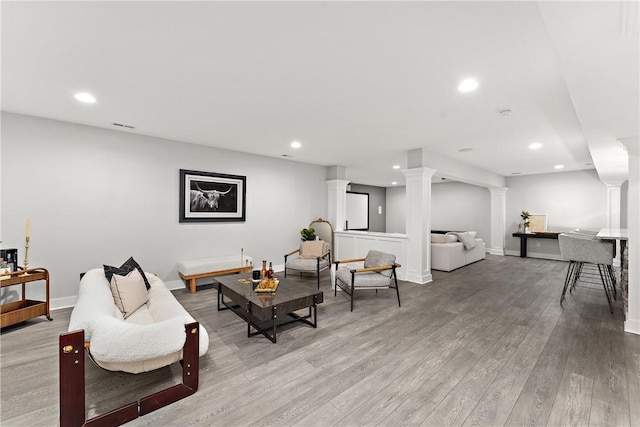 living room with light wood-style floors, recessed lighting, decorative columns, and baseboards