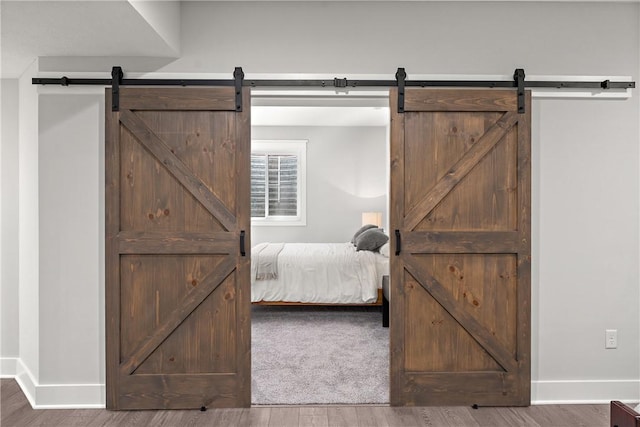 bedroom featuring a barn door and wood finished floors