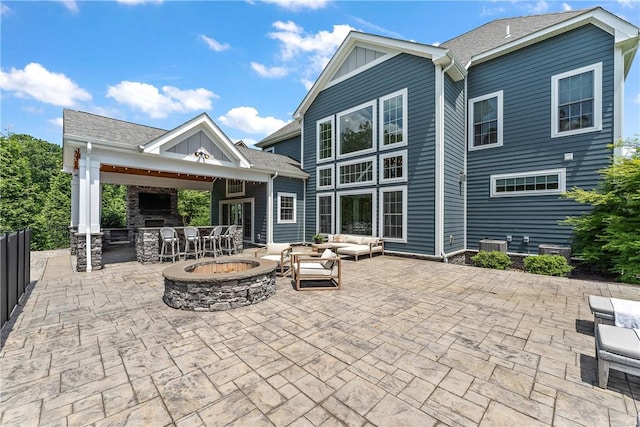 back of house with an outdoor living space with a fire pit, outdoor dry bar, board and batten siding, a patio area, and fence