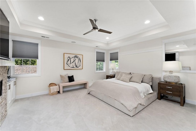 bedroom featuring a fireplace, visible vents, a raised ceiling, and multiple windows