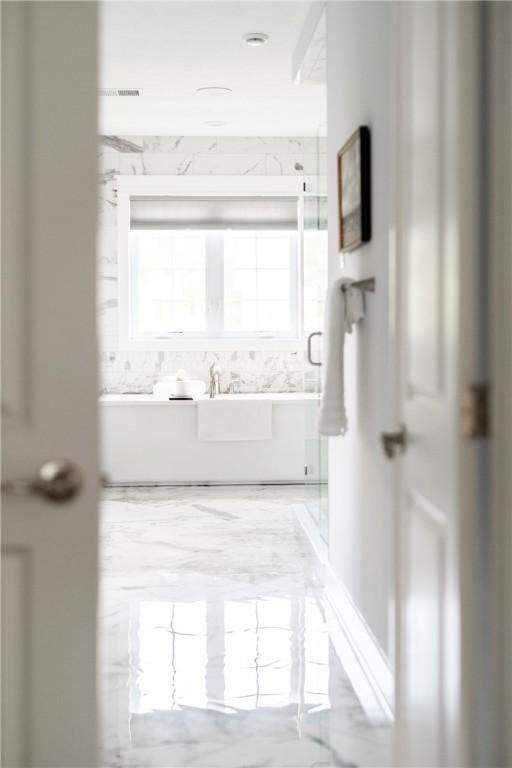 full bath with marble finish floor, a stall shower, and a soaking tub