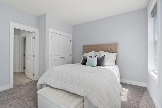 carpeted bedroom with a closet and baseboards