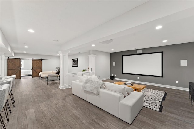 cinema room with recessed lighting, decorative columns, wood finished floors, and a barn door