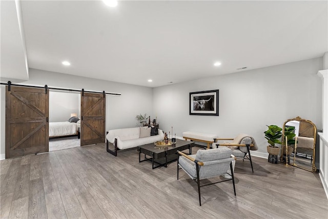 living area featuring light wood finished floors, a barn door, and recessed lighting