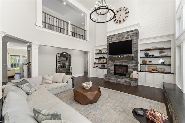 living area featuring baseboards, built in features, wood finished floors, ornate columns, and a fireplace