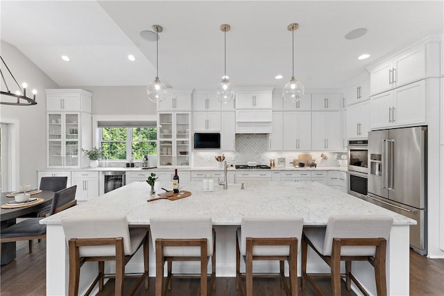 kitchen featuring wine cooler, stainless steel appliances, white cabinetry, decorative backsplash, and a kitchen bar