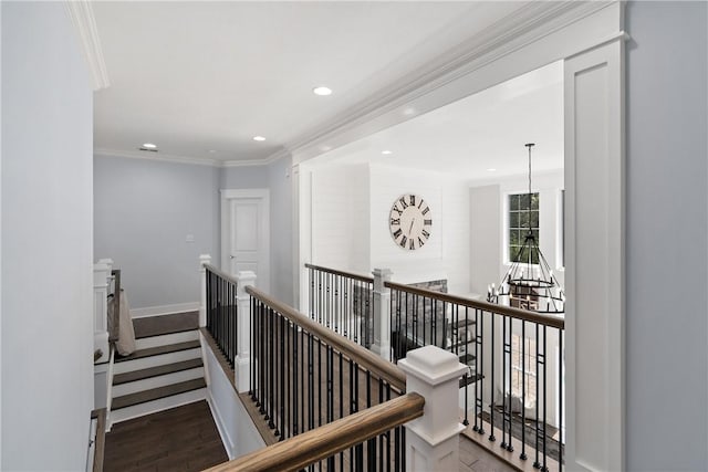 corridor featuring a chandelier, wood finished floors, an upstairs landing, baseboards, and crown molding