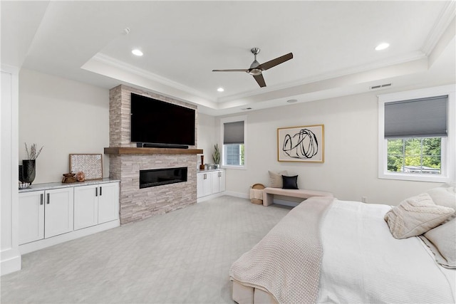 bedroom featuring multiple windows, visible vents, a raised ceiling, and light colored carpet