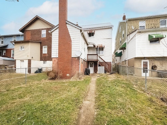 rear view of house with a fenced backyard, a lawn, and a chimney