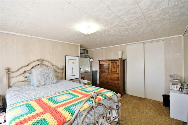 carpeted bedroom with a closet and wooden walls