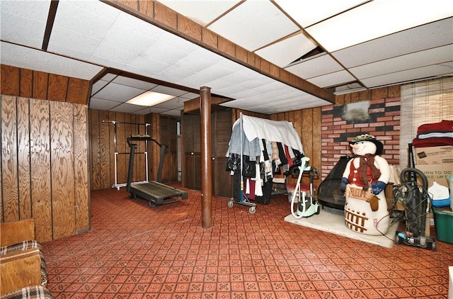 interior space featuring wood walls, a drop ceiling, and tile patterned floors