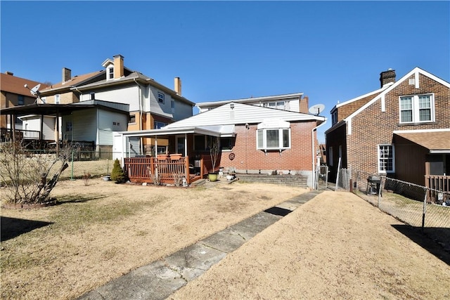 rear view of property with brick siding, fence, and a deck