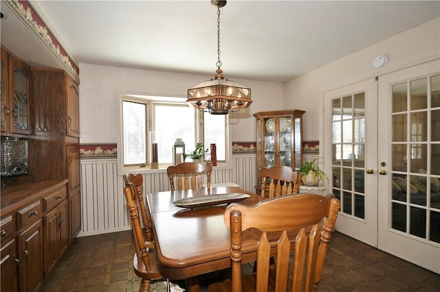 dining space featuring a wainscoted wall, an inviting chandelier, and french doors