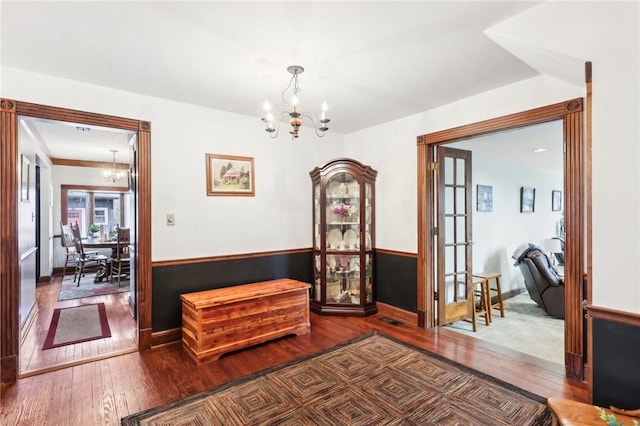 corridor featuring wood-type flooring, wainscoting, and a notable chandelier