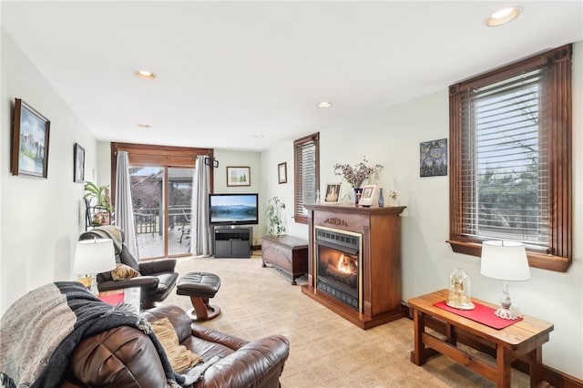 living room featuring light carpet, a glass covered fireplace, and recessed lighting