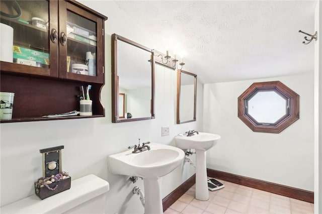 bathroom with a textured ceiling, a sink, toilet, and baseboards