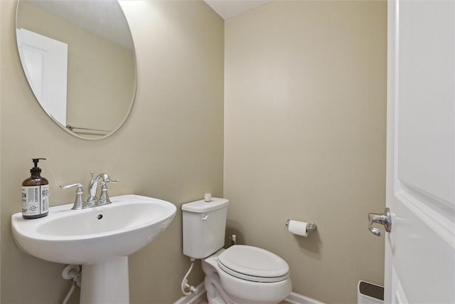 half bathroom featuring baseboards, a sink, and toilet