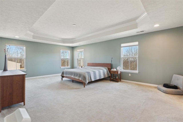 carpeted bedroom with baseboards, visible vents, a tray ceiling, and crown molding