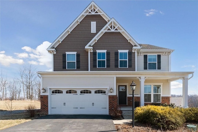 craftsman-style house with aphalt driveway, a porch, an attached garage, and brick siding