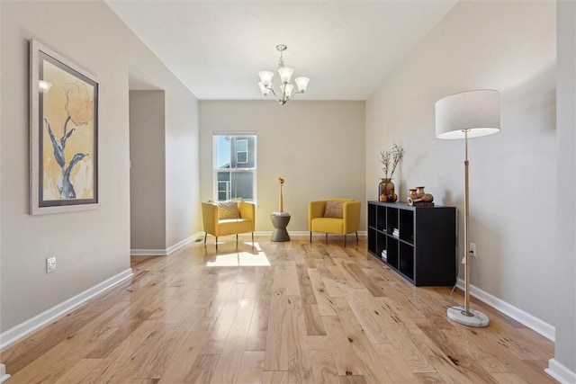 living area featuring light wood finished floors, baseboards, and an inviting chandelier