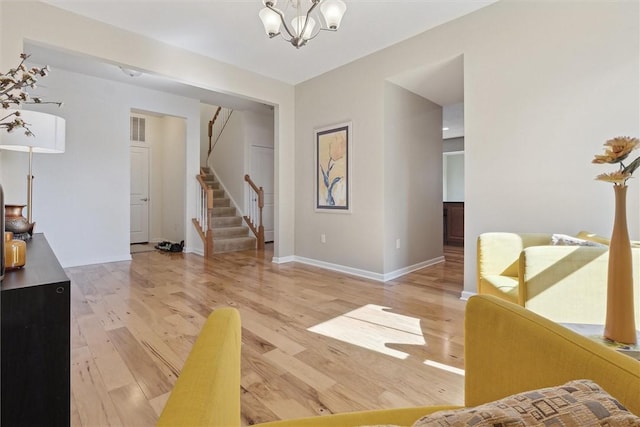 interior space featuring light wood-style flooring, visible vents, baseboards, stairway, and an inviting chandelier