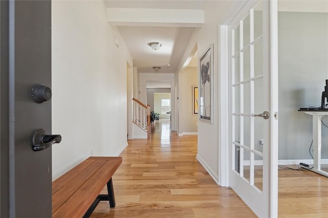 hall with stairs, baseboards, and light wood-style floors