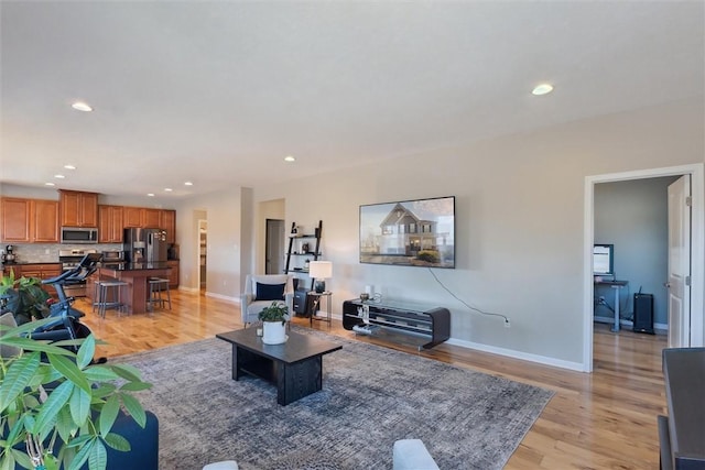 living room featuring light wood finished floors, recessed lighting, and baseboards