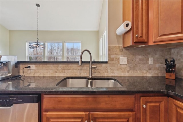 kitchen with a sink, backsplash, dishwasher, brown cabinetry, and dark stone countertops