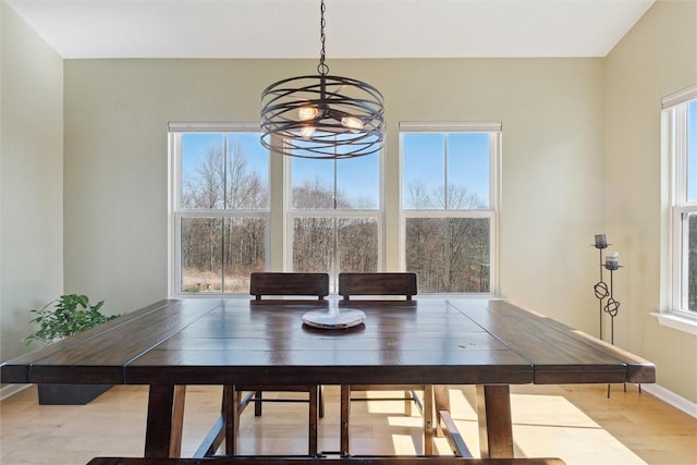 unfurnished dining area with a wealth of natural light, wood finished floors, baseboards, and an inviting chandelier