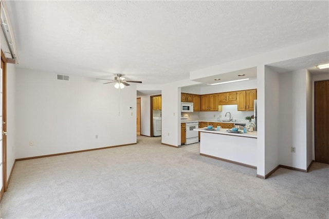 kitchen with light carpet, white appliances, a sink, visible vents, and light countertops