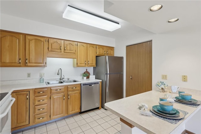 kitchen featuring recessed lighting, a peninsula, a sink, light countertops, and appliances with stainless steel finishes